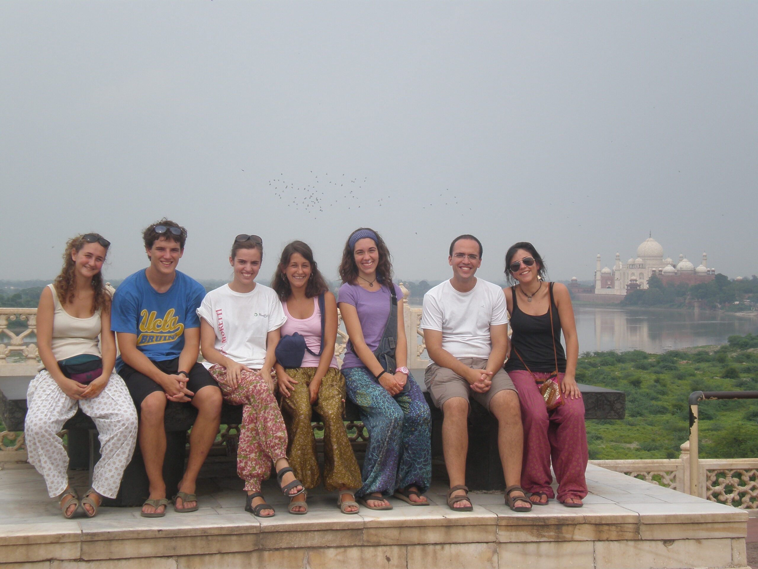 Marcos con amigos en la India, sentados en un muro con el Taj Mahal al fondo