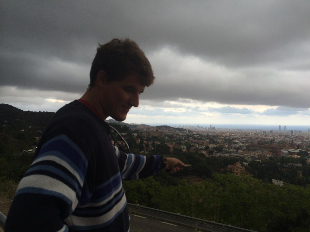Marcos Pou sonríe en un mirador de la sierra, con Barcelona y el mar al fondo bajo un cielo nublado